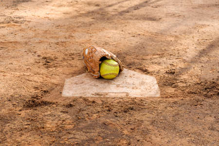 Old softball gloves and old softball balls on the homepage in a softball field.の写真素材