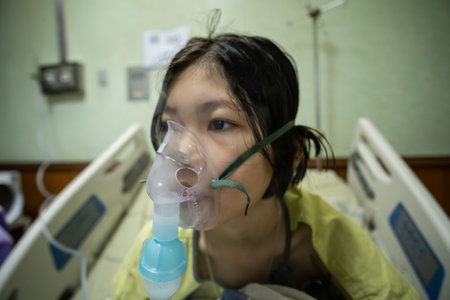 Close up sick Yong asian girl with face oxygen mask,on bed in hospital, Healthcare workers in the Coronavirus Covid19 pandemicの写真素材