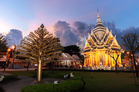 Khon Kaen, Thailand  September 21, 2009 :Khon Kaen City Shrine Illuminated at Twilight, Featuring the Golden Kalpapruek Tree Sculpture and Modern Stupa Architecture in Thailand.のeditorial素材