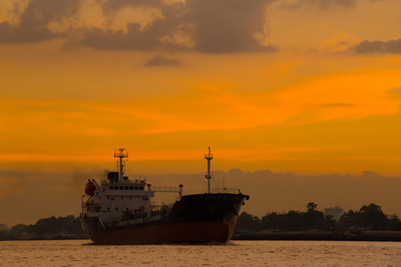 Logistics and transportation of International Container Cargo ship in the ocean at sunset,and silhouette of boatの写真素材