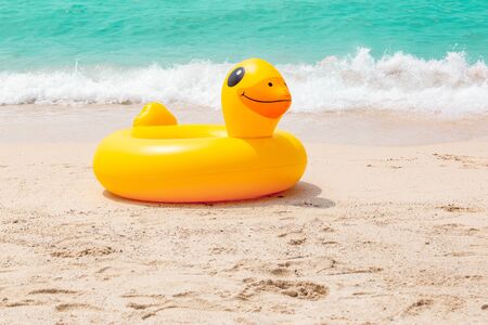 Inflatable ring player with soft wave of blue ocean on sandy beach. Background of travel in summer seasonの写真素材