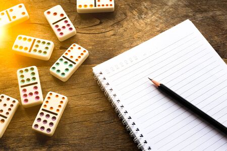 Workplace desk with notebook and pencil. Game of dominoes on wooden table. Management ideas for success. Business planning concept.の写真素材