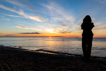 silhouette, Romantic woman  on the beach for looking sunset over the seaの写真素材