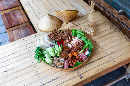GRILLED PORK WITH PICKLED FISH SAUCE and spicy sauce. Fresh vegetables and chili Surf on the banana leaf in wooden trayの写真素材