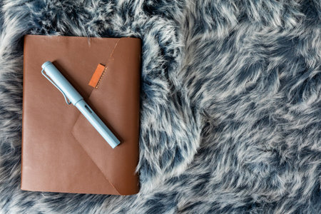 notebook with a blue pen on fur background.の写真素材