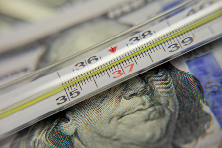 clinical thermometer over 100 dollar banknotes as symbol for high costs in health careの写真素材