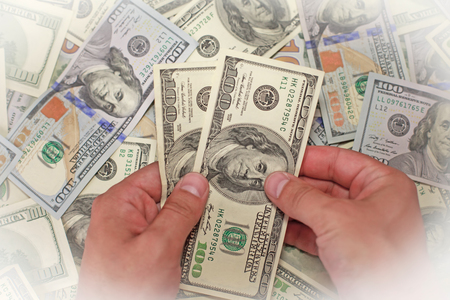 Male hand holding money in money backgroundの写真素材