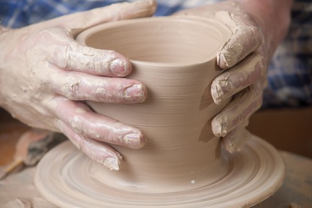 Hands of a potter, creating an earthen jar on the circle