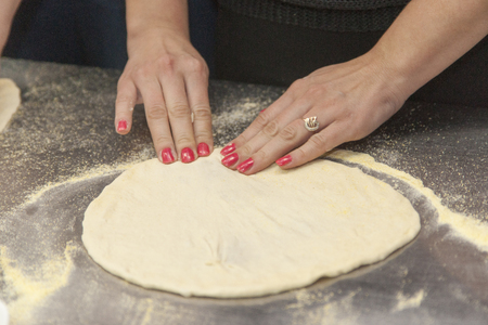 Woman chef with raw dough. Young female in uniform preparing bread dough on table.の写真素材