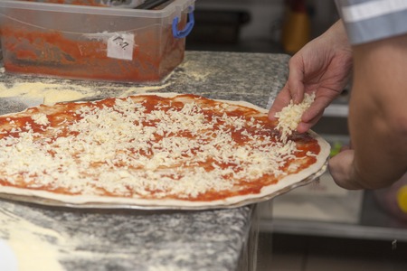 Man chef with raw pizza. Young male in uniform preparing pizza on table.の写真素材