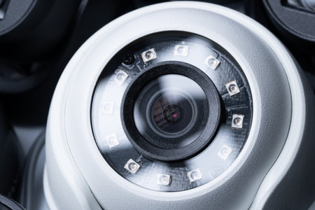 Close-up white security camera with black cameras nearby.