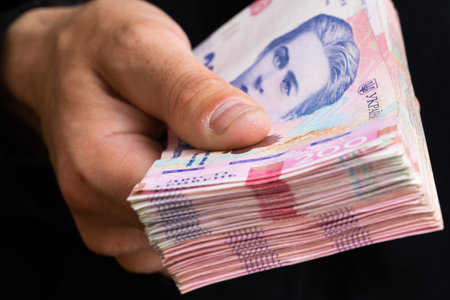 Hand with hryvnia banknotes, money of Ukraine. Small depth of field.