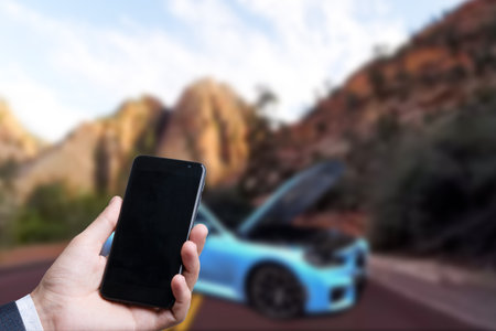 Man use mobile phone, blur image of the car is broken down as backgroundの写真素材