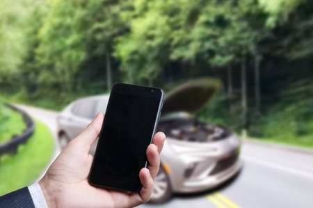 Man use mobile phone, blur image of the car is broken down as backgroundの写真素材