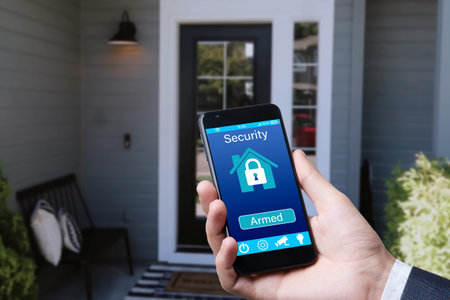 man controls smart home devices using app for mobile phone on background of the front door. concept of digitalization. a mockup with hand holding phoneの写真素材