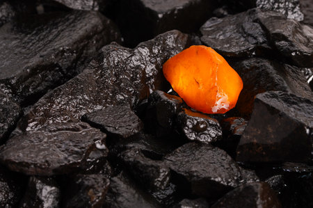 The beauty of natural raw amber. A piece of yellow-red transparent natural amber on a piece of stone woodの写真素材