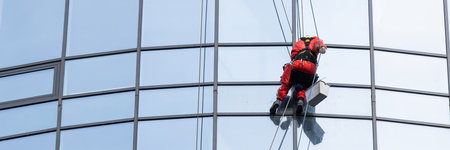 Portrait of a window cleaning technician at work on a high-rise building, maintaining clear and...