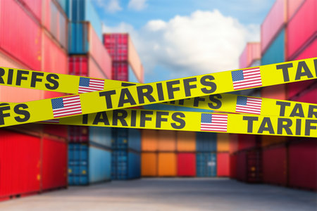 Bright yellow signage displaying tariff warnings is prominently placed among stacks of colorful shipping containers. The setting emphasizes trade regulations in a busy port environment.の写真素材