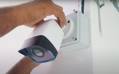 Close-up shot of a technicians hands installing a CCTV camera on a wall, showcasing the setup...