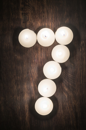 Lit candles on a wooden background in the form of a numberの写真素材