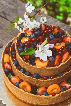 Closeup of the apple and cherry flowers on cheesecake with fruits and berries on the old planksの写真素材