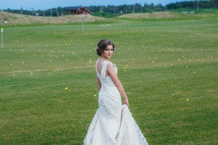 Beautiful bride in wedding dress on the green field of the golf clubの写真素材