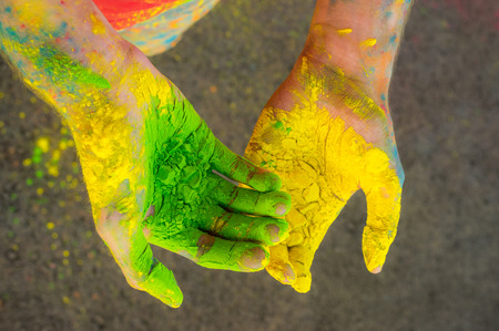 Two hands with green and orange dry hawley paintの写真素材