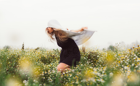 Portrait of young girl dancing in chamomile field in sunriseの写真素材