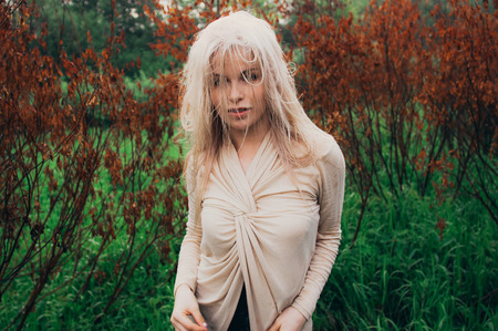 Portrait of young girl dancing between dead trees, in motion with hair on face