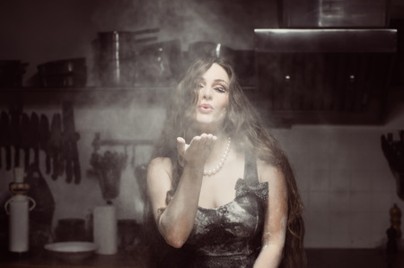 Beautiful hostess spray flour, portrait in flour fog, closed eyesの写真素材