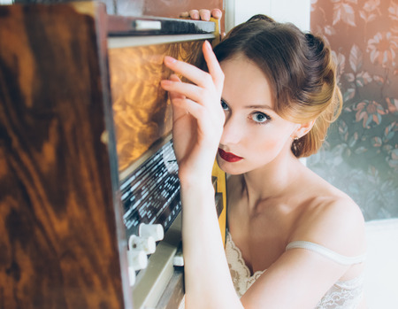 Beautiful portrait of young girl in retro style on fur, old radio, looking to the cameraの写真素材