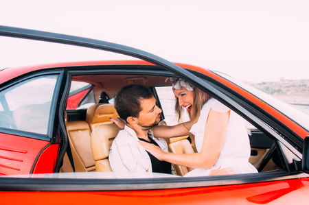 Young girl in white dress and man sitting on the front seat of the red car, seaside of Maltaの写真素材