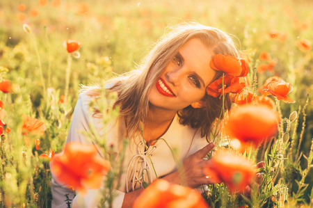 Beautiful girl in the field and poppy flowers, looking to the cameraの写真素材