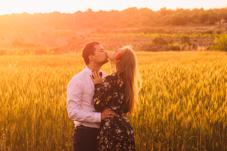 Man and woman with closed eyes embracing and kissing in wheat field on the dusk,  countryside Maltaの写真素材