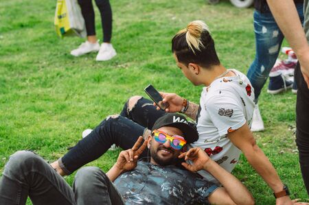 Helsinki, Finland - June 29, 2019:  Two guys sitting on the grass on Helsinki Pride festival in...