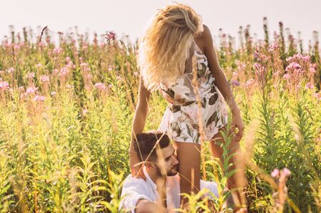 Young man and woman together in the field on sunsetの写真素材