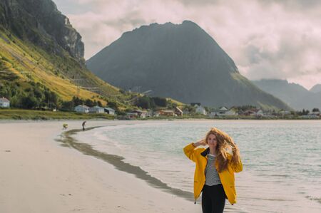 Girl in yellow jacket on the white sand  beach in Ramberg on Lofoten Islands, Norwayの写真素材