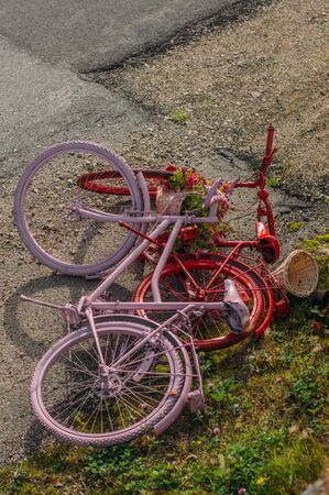 Two painted bicycles - red and pink lies on earthの写真素材
