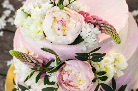 Big pink wedding cake decorated by natural flowers