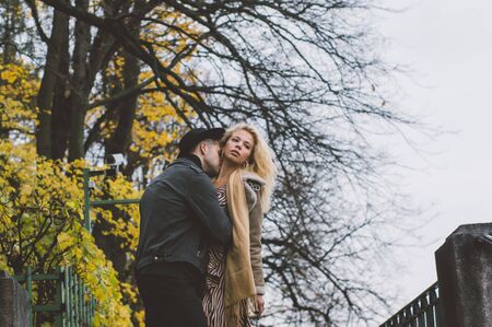 Couple walking and kissing in public park, fall season with a lot of yellow treesの写真素材