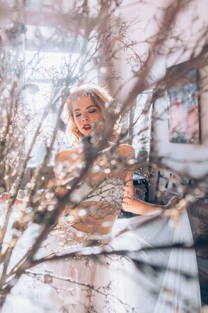 Beautiful blond girl with closed eyes and vintage make up and hairstyle dancing in lingerieの写真素材