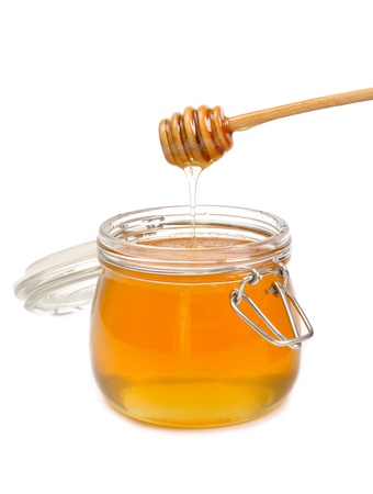 Jar of honey with wooden drizzler isolated on white の写真素材
