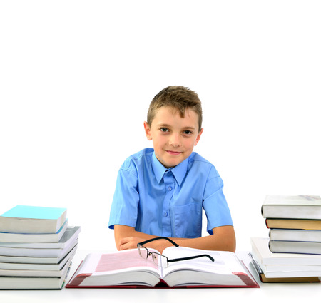 Young happy boy looks like a businessman sitting between books の写真素材