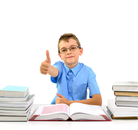 Young happy boy looks like a businessman sitting between books and shows thumb okの写真素材