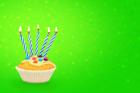 Birthday cupcake with candles on green confetti background の写真素材