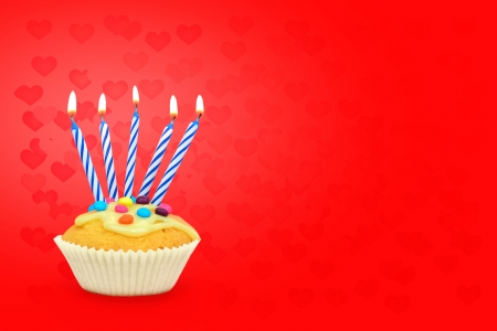 Birthday cupcake with candles on red hearts background Text space の写真素材