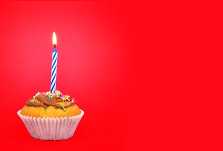 Birthday cupcake with candle on red background Text space の写真素材