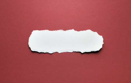 A piece of torn paper on a red background. Space for text.の写真素材