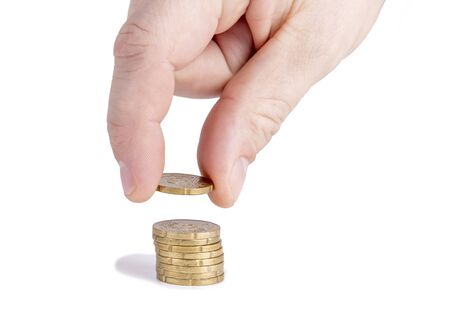 Man's hand put money to stack of coins.の写真素材