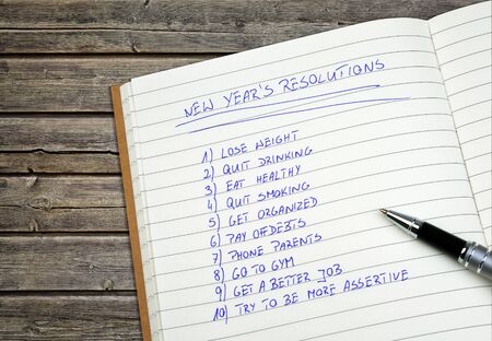 New Year resolutions listed in a notpad. Wodden background.の写真素材